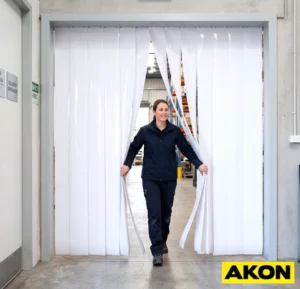 White PVC strip curtain installed in an industrial doorway to divide work areas or control temperature.