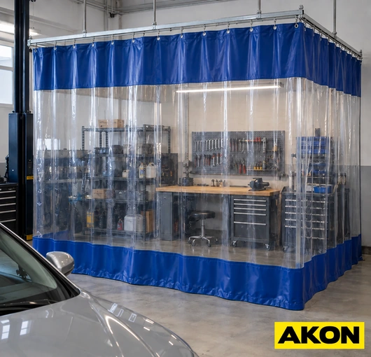 A blue and clear PVC curtain booth enclosing a workstation in an automotive workshop.