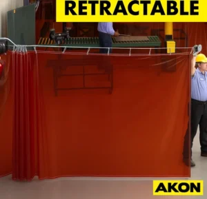 A retractable welding screen extended in an industrial workspace to contain sparks and shield workers from arc flash.