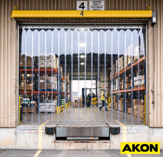 Clear PVC strip flaps installed across an extra-wide loading dock door opening in an industrial facility.