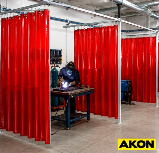 Transparent amber welding curtains hanging in an industrial workspace to contain sparks and shield nearby workers.