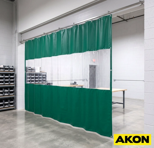 Industrial room divider curtains hanging from a ceiling-mounted track to separate a large facility into distinct work areas.