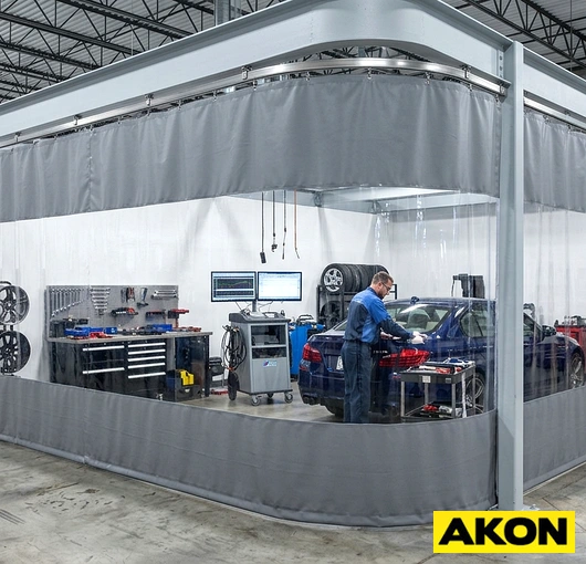 Industrial isolation curtains hanging in a factory or warehouse to separate work zones and contain dust, noise, or temperature.
