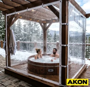Clear vinyl tarp enclosing an outdoor hot tub on a deck with a mountain view in winter conditions.