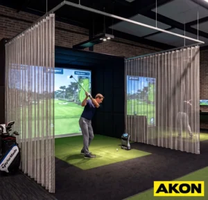 Steel mesh curtains installed along the boundary of an indoor golf enclosure to contain errant balls.