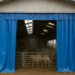 Blue industrial curtain wall at the entrance of a barn, used for climate control in barns and animal facilities to maintain temperature and protect livestock inside