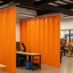 Bright orange Makerspaces and Hackerspaces curtains dividing dedicated work zones with 3D printers, woodworking stations, and creative tools in a shared workshop