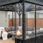Black pergola with clear vinyl side panels enclosing a cozy outdoor lounge in snow – Pergola Side Panels Temporary Winter Solutions That Look Built-In