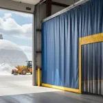 Blue industrial Curtain Walls for City Public Works Yards and Salt Dome Storage Areas with strip door access, separating interior workspace from outdoor salt dome and equipment