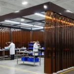 Brown tinted curtain wall enclosure designed to enclose quality control area for inspections, providing separation and compliance