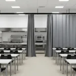 Curtain Walls for Blocking Off Cafeteria Equipment During Non-Use Hours, gray track-mounted curtains spanning the room to separate kitchen and tables