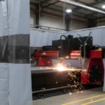 Gray plasma burn table enclosure with black vision panels and welding curtains blocking sparks Plasma Burn Table Enclosures Containment with Welding Curtains