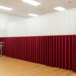 How dance studios use curtain walls for private lessons or auditions, with a red and white divider creating a private practice space inside a mirrored studio