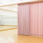 How dance studios use curtain walls for private lessons or auditions with soft pink fabric dividers separating mirrored practice areas