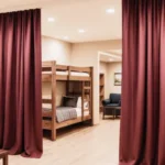 Industrial curtains for dividing large Airbnb properties or group lodges, with burgundy fabric creating private sleeping and lounge spaces in shared rental areas