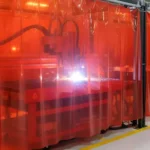 Red vinyl welding curtain enclosure around plasma burn table, fully containing sparks and light Plasma Burn Table Enclosures Containment with Welding Curtains