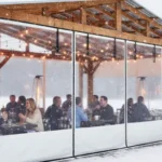 Restaurant patio enclosed with solid and clear vinyl panels to maintain comfort during winter Extend Patio Season Restaurant and Café Enclosure Ideas For Winter