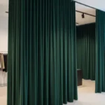 Retail showroom curtains in hunter green creating stylish fitting room dividers in a modern clothing store