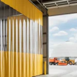 Yellow vinyl Curtain Walls for City Public Works Yards and Salt Dome Storage Areas with clear panels dividing indoor workspace from outdoor salt dome and snow equipment