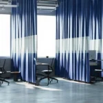 Modern open-plan workspace with blue partition curtains for office separating desks for privacy and noise control.