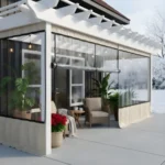 White-frame patio enclosure for protecting plants during winter, designed with transparent vinyl walls and a bright seating area surrounded by greenery