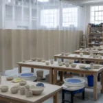 Beige and clear vinyl curtain wall dividing the glazing zones from pottery wheels and worktable in a ceramic classrooms
