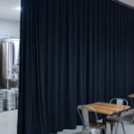 Black sound-absorbing curtain wall dividing brewery brewing tanks and tasting tables