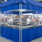 Blue industrial curtain enclosure at a stadium concession stand, providing full separation and visibility for food preparation