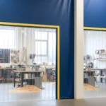 Blue industrial curtain wall with clear strip door panels enclosing a woodturning space to keep chips contained inside the workstation