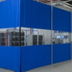 Blue modular curtain enclosure with clear sections surrounding EV battery-testing equipment