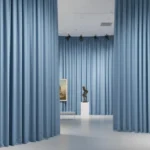 Blue museum exhibit divider curtains shaping open gallery pathways for modern sculpture displays