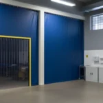 Blue vinyl curtain walls with a clear strip door creating a secure temporary room inside a detention center