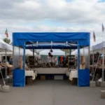 Blue vinyl farmers market booth enclosure providing weather protection and display separation at an outdoor craft fair