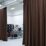 Brown curtain partitions separating equipment zones inside an electric vehicle battery-testing laboratory