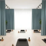 Calming blue Yoga & Wellness Zone Divider Curtains dividing yoga mats in a wellness studio with ample natural light and plants