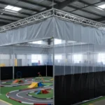 Clear modular curtain RCdrone course with black trim – “Indoor drone and RC course enclosed by transparent modular walls with black trim, illustrating adjustable track layout and spectator safety.