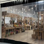 Clear vinyl curtain wall enclosure separating vendor displays at an indoor farmers market