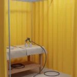 Compact yellow vinyl spray booth enclosure set up for small spray foam or coating projects in a workshop