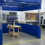 Freestanding blue vinyl spray booth enclosure with clear window panels for visibility and overspray control