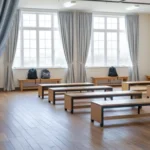 Gray fabric curtains dividing a bright wooden room with benches and large windows, creating a private multipurpose area