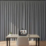 Gray video call backdrop curtain behind desk with laptop, creating a distraction-free workspace