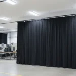 Heavy-duty Vinyl Fabric Enclosure Curtains separating work zones in an industrial environment, enhancing privacy and safety