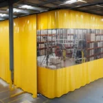 Large yellow training enclosure curtain with a clear viewing window used to separate an indoor industrial training zone for confined-space simulations
