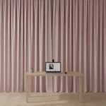 Pink backdrop curtain behind a minimalist desk setup for professional video calls