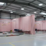 Pink modular curtain RCdrone course – “Indoor RCdrone course using pink modular curtain walls in a large shared space, demonstrating flexible partitions and safe zones for participants.