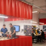 Red and clear vinyl curtain walls used in a robotics lab to separate work zones and reduce noise in educational environments