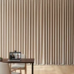 Taupe video call backdrop curtain in a bright workspace, with a desk and laptop for remote meetings