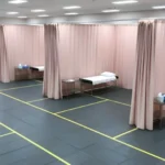 Temporary medical facility with pink curtain partitions and floor markings, optimizing patient zones and movement for NGOs or emergency clinics