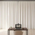 White video call backdrop curtain with desk and laptop in a well-lit home office environment