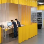 Yellow and transparent curtain walls dividing work areas in a science museum, showing flexible space design for educational exhibits